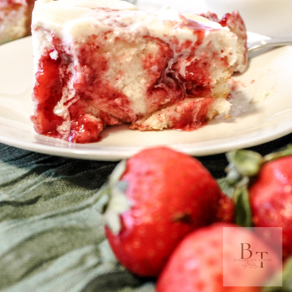 white cake with strawberry filling, sitting on a white place with a green linen cloth
