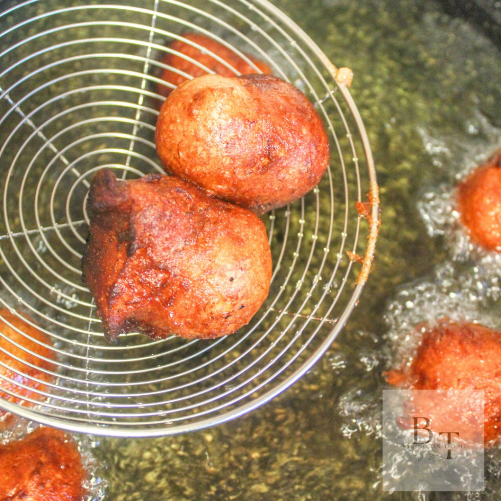 freshly fried banana gulgulas aka Indian banana fritters being taken out of the oil